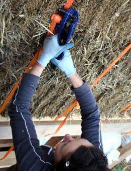 Tensioning a completed strawbale wall with a tensioning tool.